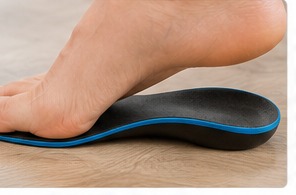 A supportive orthotic insole with a moulded arch beneath a bare foot.