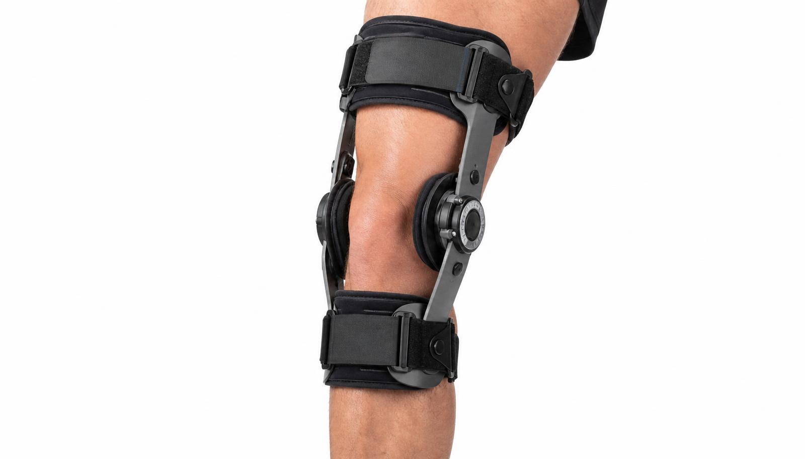 A leg wearing a rigid unloader knee brace with an aluminium frame, side uprights and a dial hinge at the knee.